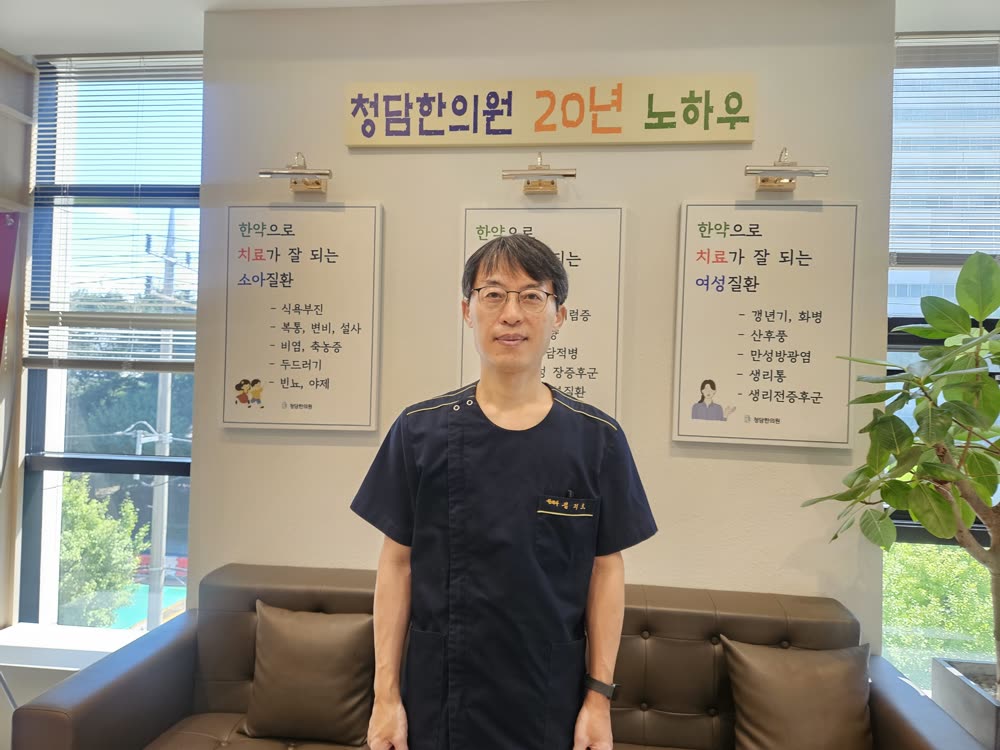 청담한의원 20년 노하우 게시판 앞의 김지호 대표원장 (광주 수완지구)
